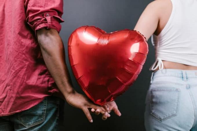 Par drži crveni balon u obliku srca