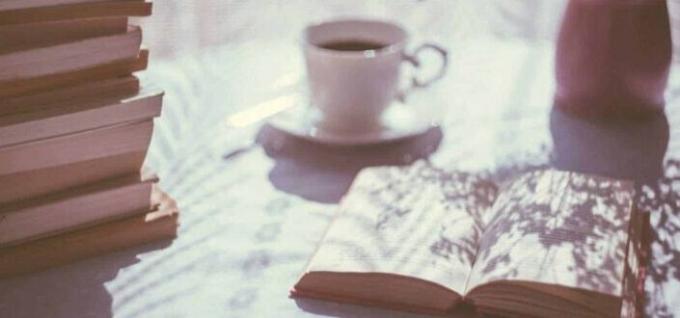 ספר פתוח ליד כוס תה קרמיקה לבנה על צלוחית