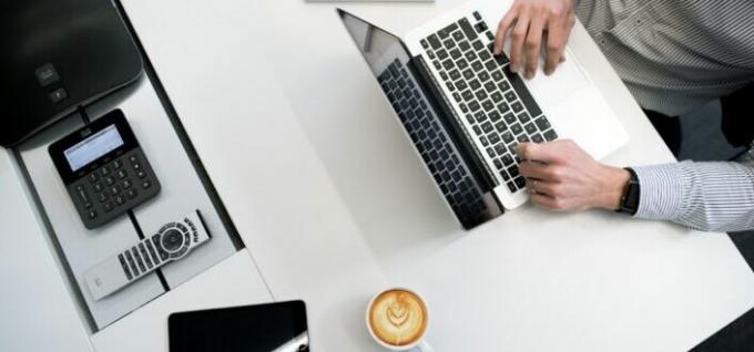 person, der bruger sin bærbare computer med kaffe på siden