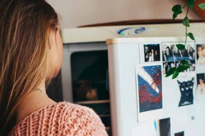 Женщина заглядывает внутрь холодильника